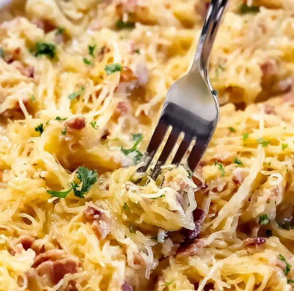 Bowl of healthy spaghetti squash carbonara topped with parsley and parmesan cheese.