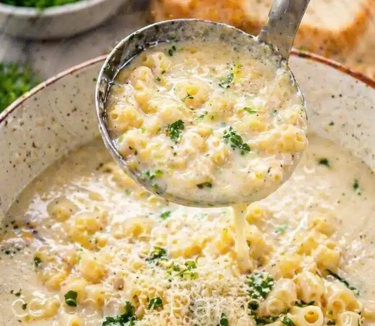 Bowl of Garlic Parmesan Pasta Soup with fresh herbs and grated cheese